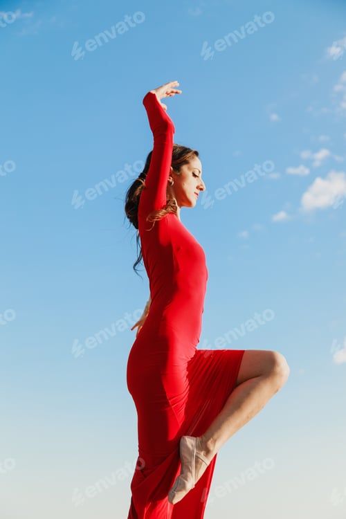 Preview: Artistic pose of woman in red dress on rocks in Calabria