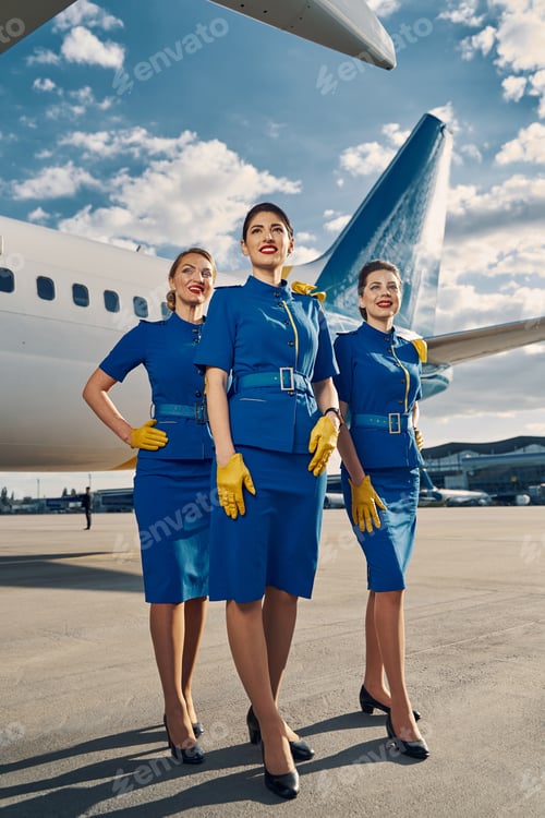 Preview: Three smiling female flight attendants looking into the distance