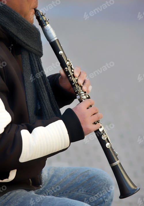 Preview: A diverse male street musician plays sweet sounds on a clarinet outside on a cold winter day