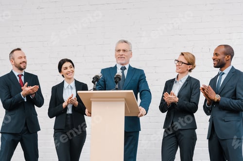 Preview: multicultural businessmen and businesswomen applauding to bearded speaker