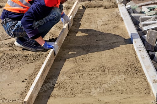 Preview: Closeup shot of a construction worker leveling a sandy platform with a wooden board