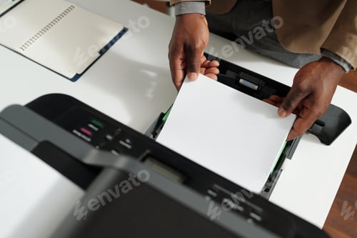 Preview: Above angle of hands of young office worker putting paper into xerox tray