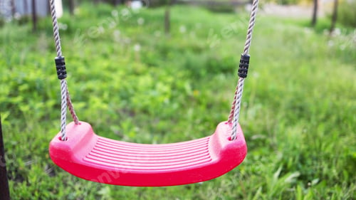 Preview: Lonely swing hanging in a garden full of green grass and trees in springtime