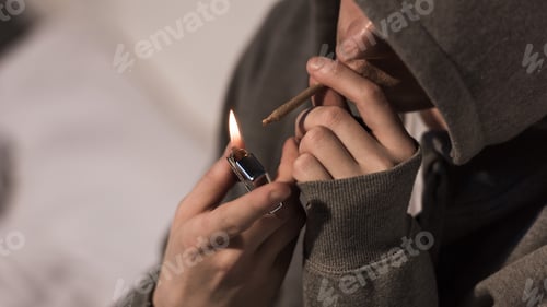 Preview: selective focus of junkie man lightening rolled marijuana cigarette