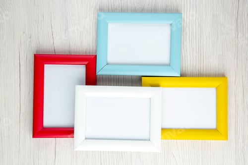 Preview: Overhead view of four empty picture frames in different colours on white stripped background