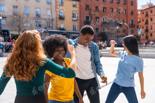 Preview: Multi ethnic young friends dancing in a city square, having a good time together in the city