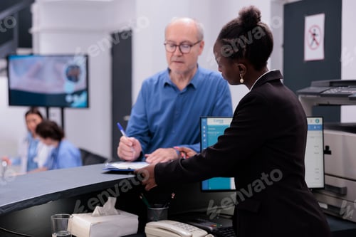 Preview: Rception worker standing at hospital counter discussing medical expertise with senior patient