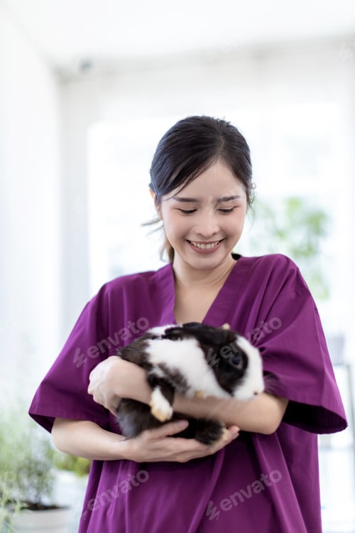 Preview: Woman holding cute fluffy Bunny at home. Friendship with Easter Bunny.
