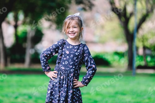 Preview: Portrait of happy little girl in dress standing in the park
