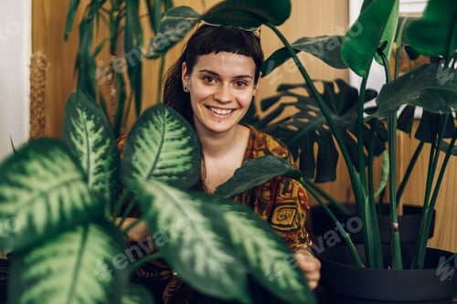 Preview: Fashionable young woman taking care of her house plants