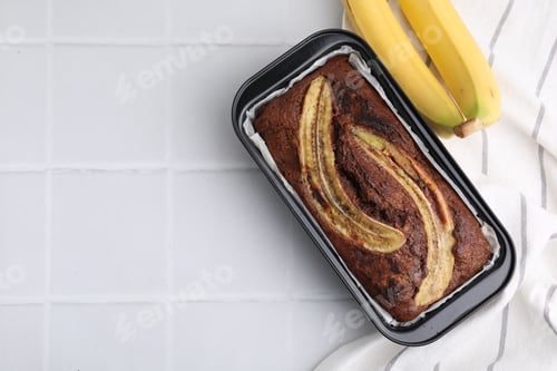 Preview: Delicious banana bread and fresh fruits on white tiled table, top view. Space for text