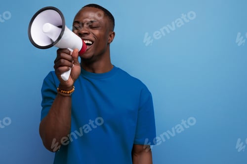 Preview: young successful handsome american guy dressed in a basic t-shirt speaks news into a megaphone