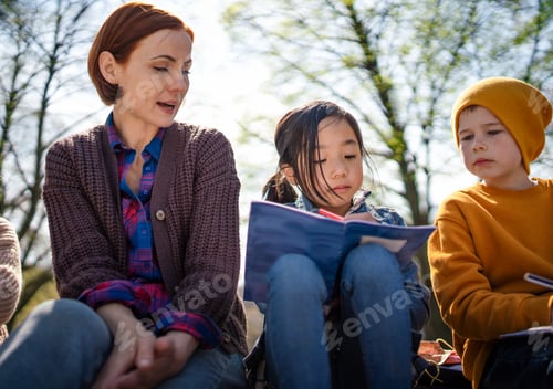 Preview: Teacher with small children sitting outdoors in city park, learning group education concept
