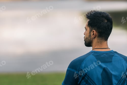 Preview: Back of a sportive man facing a lake in a park