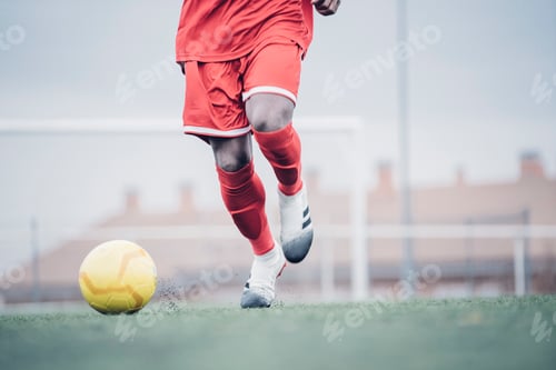 Preview: African soccer player with red outfit playing soccer.