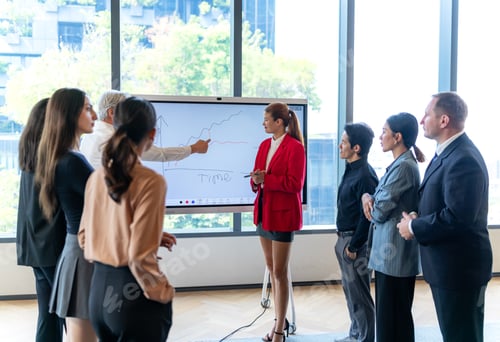 Preview: Diverse business team collaborates on a financial graph presented on a digital whiteboard