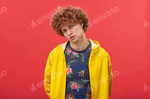 Preview: Cool male fashion model with curly red hair and blue eyes tilting head sideways having serious and c