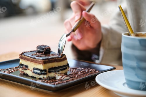 Preview: Unrecognizable woman eating a cake and drinking coffee in a cafe.