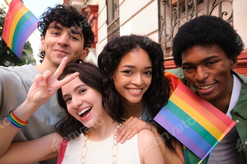 Preview: Young activists showing peace sign and holding rainbow flags are taking selfie at pride parade