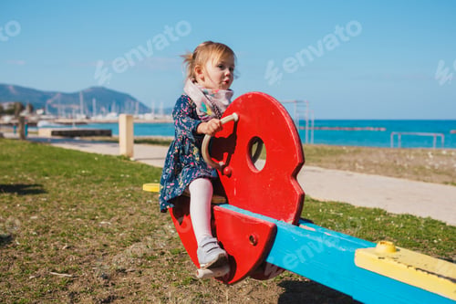 Preview: summer, childhood, leisure and people concept - happy little girl on children playground