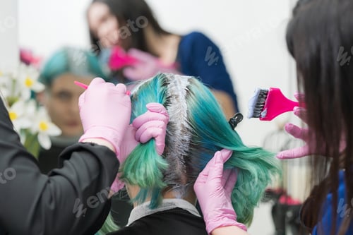 Preview: Process of hair dyeing in salon. Two hairdressers applying paint to hair during bleaching hair roots