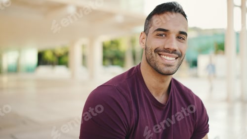 Preview: Young man dressed casual looking at camera and smiling waiting someone on the street