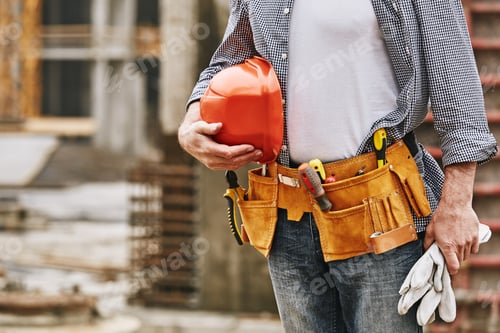 Preview: Cropped image of male builder with helmet and tool belt