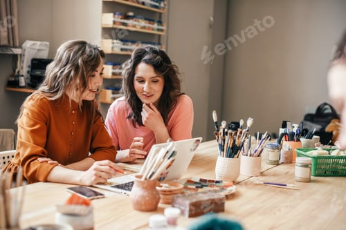 Preview: Two young women are sitting at table with a laptop