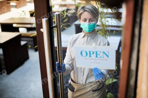 Preview: Young waitress reopening restaurant for delivery and takeaway only during coronavirs epidemic.