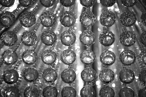 Preview: Closeup of a crystal chandelier with the reflection of light in strung crystal balls, in grayscale