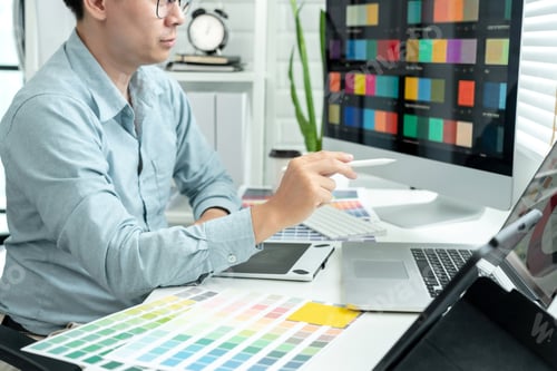 Preview: Male graphic designer is choosing color swatch samples on multiple screens and sketching on tablet