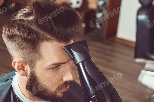 Preview: The hands of young barber making haircut to attractive man in barbershop