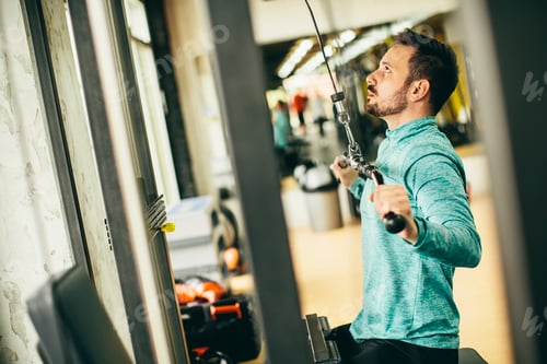Preview: Young man doing exercise for triceps in the gym on mashine