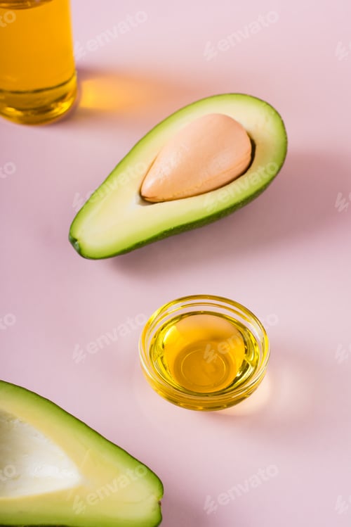 Preview: Ripe avocado and avocado oil in a bowl and bottle. Home beauty treatment. Vertical view