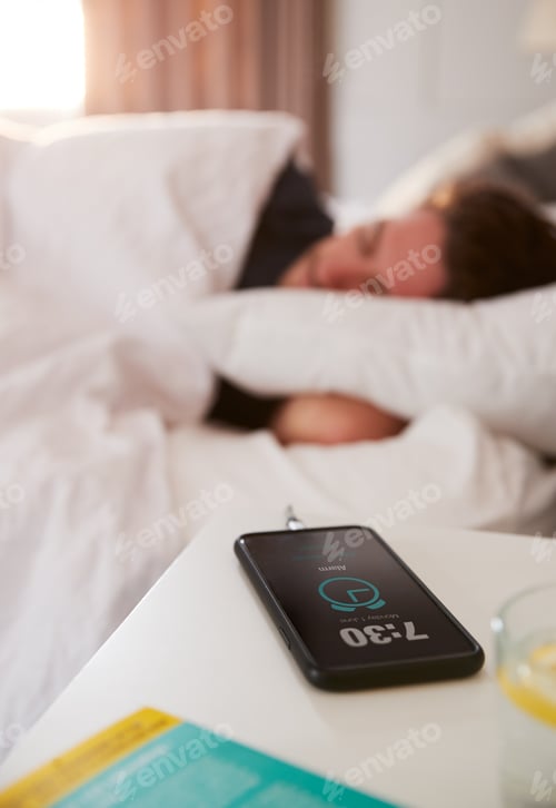 Preview: Man Asleep In Bed With Mobile Phone On Bedside Table