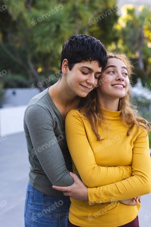 Preview: Happy biracial lesbian couple standing on garden terrace embracing and smiling