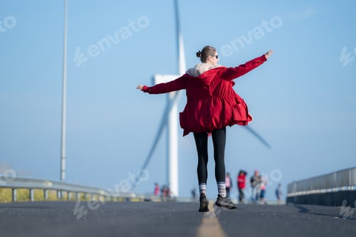 Preview: On the background of windmills, A young woman in a red jacket is enjoying her winter vacation.