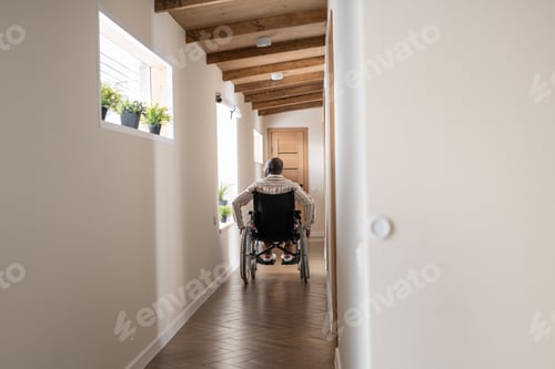 Preview: Back view of man with paralysis moving on wheelchair along corridor