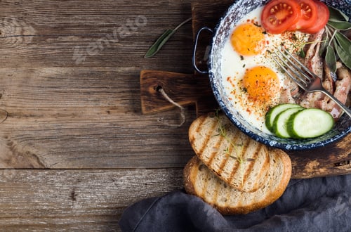 Preview: Breakfast set. Pan of fried eggs with bacon, fresh tomato, cucumber, sage and bread