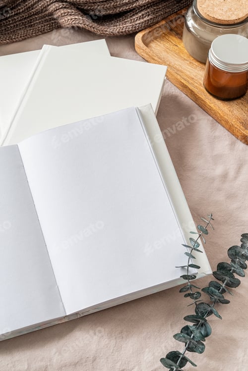 Preview: Opened book, candles and eucalyptus leaves top view on white bed. Mock up design