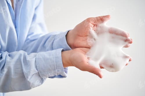 Preview: Hands in a blue shirt hold a savory facial foam demonstrating its texture.