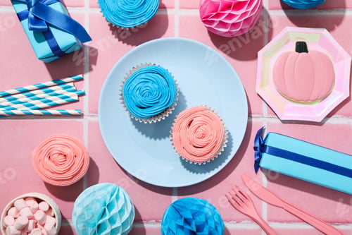 Preview: Gift boxes and cupcakes on plates on pink background, top view