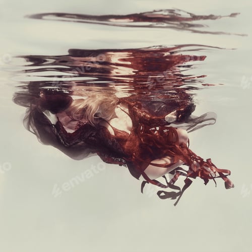 Preview: A Woman In A Red Dress With Ribbons And Airy Fabric Poses Underwater Against A Light Background As