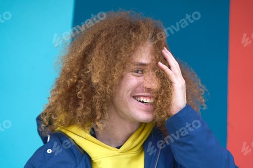 Preview: Smiling young man with curly hair against colorful background