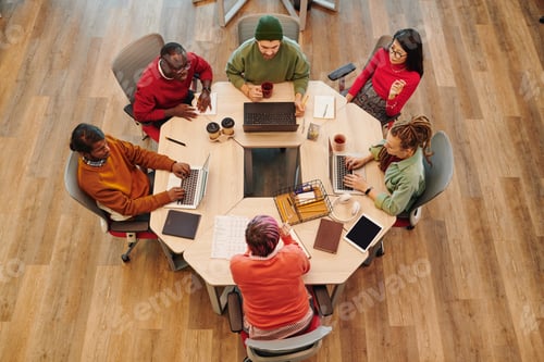 Preview: Medium group of young intercultural creative designers gathered by table
