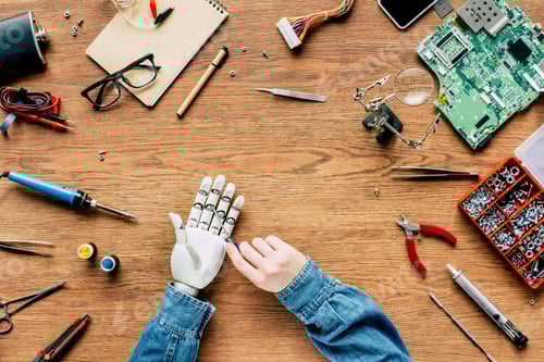 Preview: cropped image of man fixing robotic hand by screwdriver at wooden table