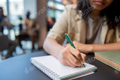 Preview: Young student with pen making notes on page of copybook