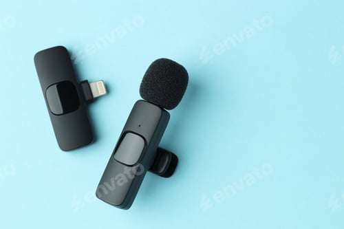 Preview: Lavalier microphone and wireless receiver on light blue background, flat lay. Space for text