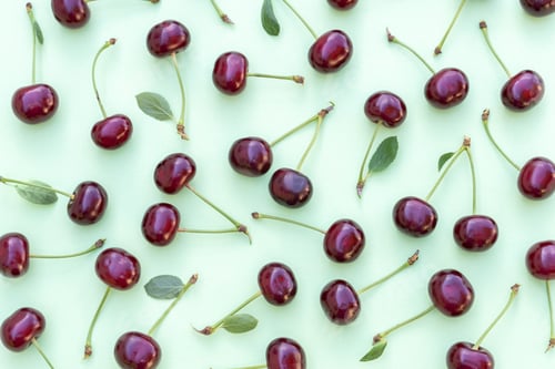 Preview: Cherry pattern. Flat lay of cherries and leaves on a soft green background.