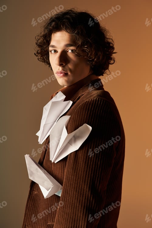 Preview: Young man with curly hair in a brown corduroy blazer with paper planes